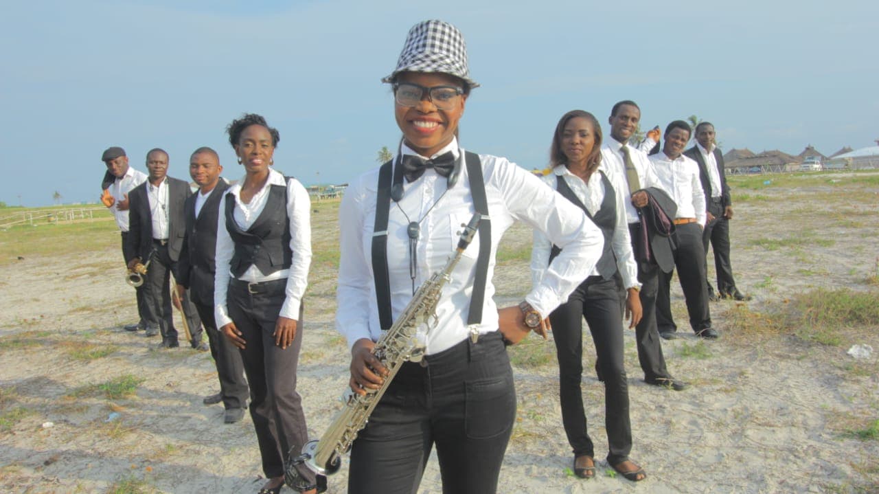 Funmisax leading her band — matching black and white outfits on a Lagos beach