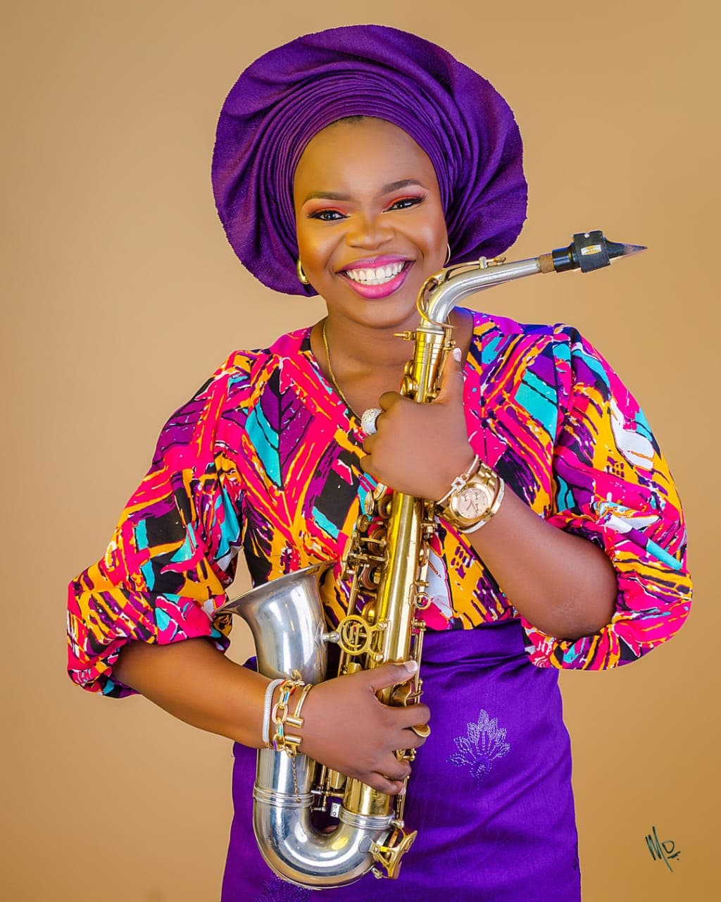 Funmisax in colorful ankara attire holding her saxophone